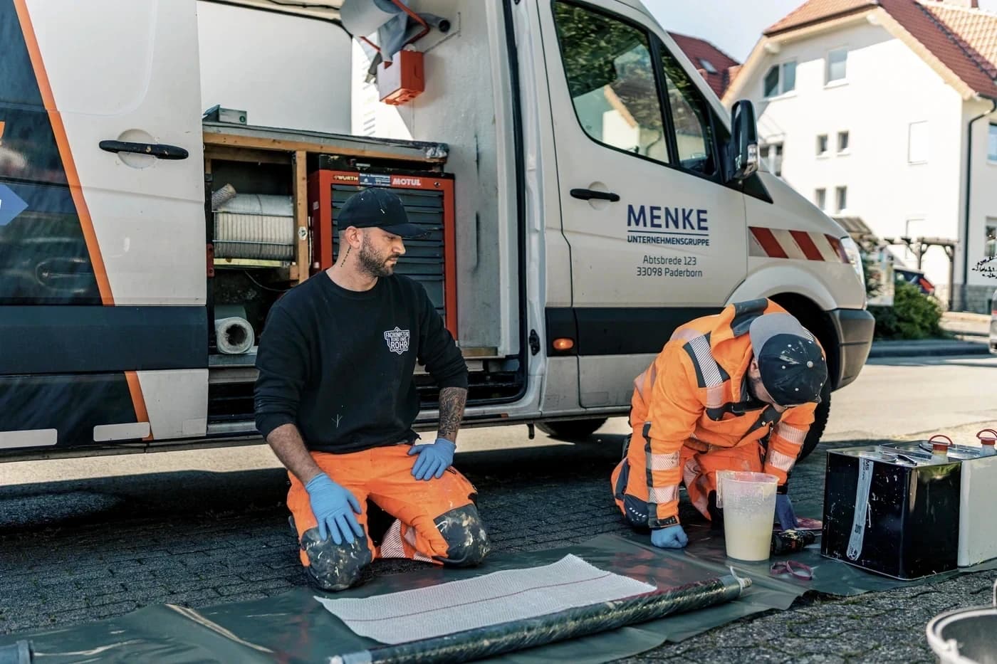 Zwei Monteure von Menke Umweltdienste bereiten am Einsatzfahrzeug die Kanalsanierung vor