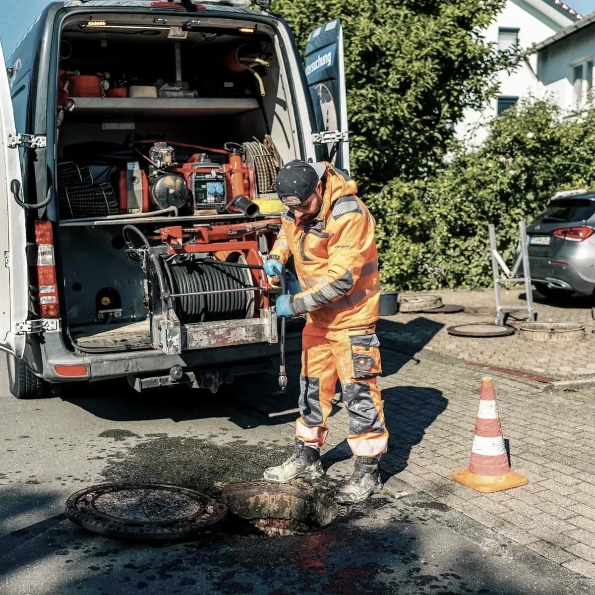 Monteur von Menke Umweltdienste arbeitet am geöffneten Schacht vor dem Einsatzfahrzeug
